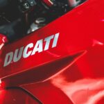 A detailed view of a red Ducati motorcycle dashboard and handlebars.