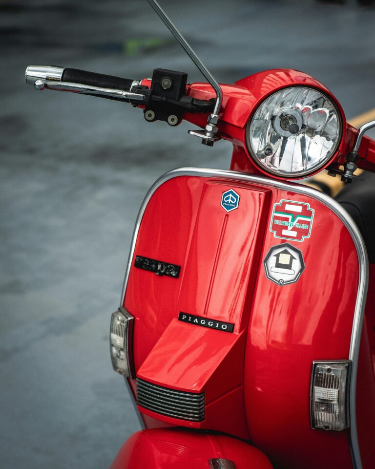 Close-up of a classic red Vespa scooter with Italian design elements, perfect for vintage vehicle enthusiasts.
