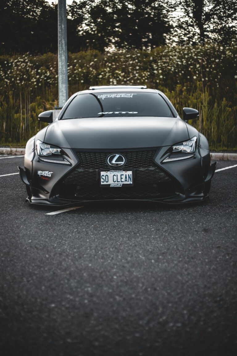 Front view of a sleek black Lexus with custom license plate in a parking lot.
