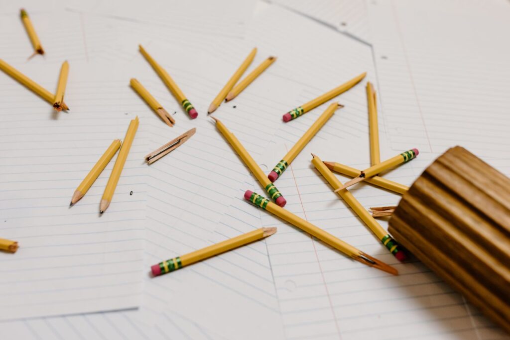 Scattered broken pencils on papers depict workplace stress or burnout.